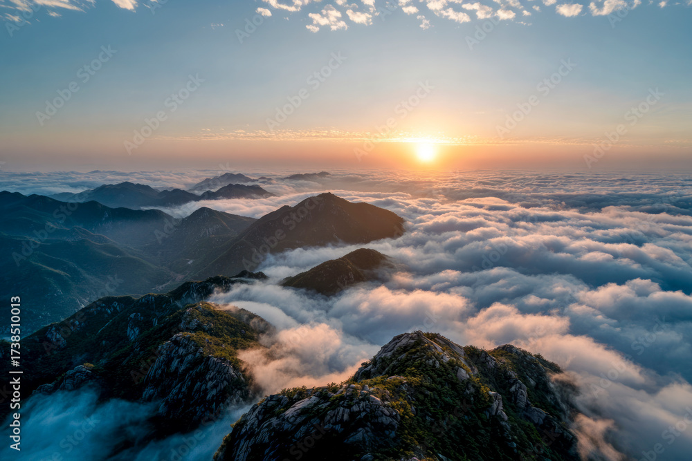 Fototapeta premium Sun rising over mountain peaks overlooking a sea of clouds