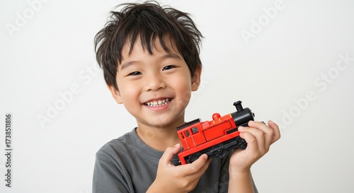 Happy Young Boy Holding a Red Toy Train Isolated on White Background