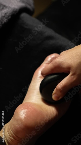 stone massage. stone therapy. masseuse. masseuse doing foot massage with a stone