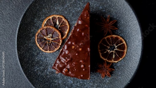 A slice of sweet layered cake covered in chocolate with nuts and caramel. A slice of chocolate cake