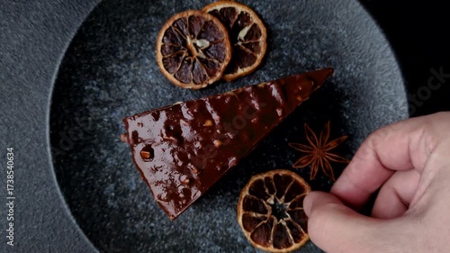 A slice of sweet layered cake covered in chocolate with nuts and caramel. A slice of chocolate cake