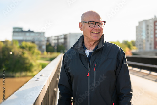 Portrait of a smiling senior man standing on a bridge in the city