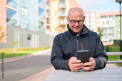 Portrait of a senior man using his mobile phone in the city while sitting
