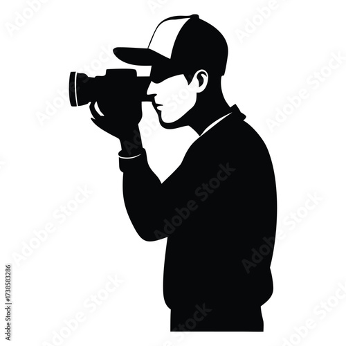 Silhouette of a person wearing a hat holding and operating a video camera