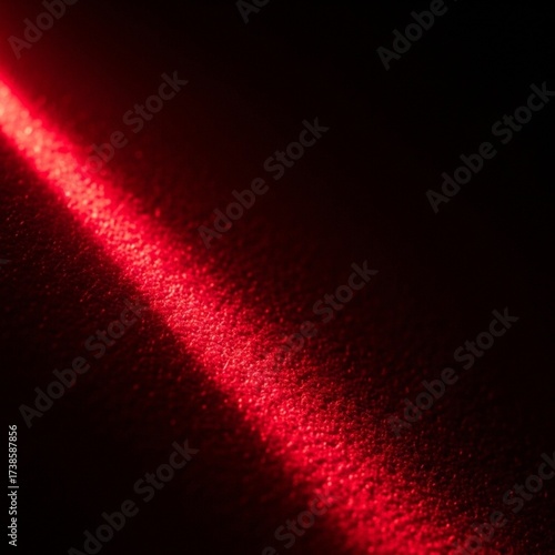 Red light beam on dark textured surface, creating a dramatic effect.