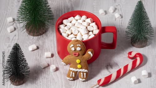 Festive gingerbread cookie and hot chocolate with marshmallows on a wooden table in a cozy winter setting