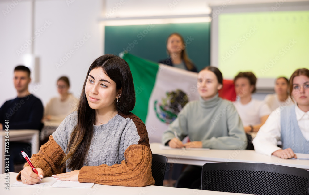 Fototapeta premium Young female student attentively listening to a lecture in a classroom