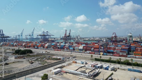 Aerial drone view of Valencia commercial port with shipping containers, cranes, and cargo ships