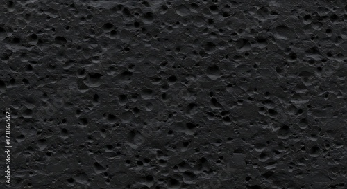 Black vesicular basalt or scoria texture. A top-down, macro photograph of a porous igneous rock, showcasing its natural holes and rough geology
