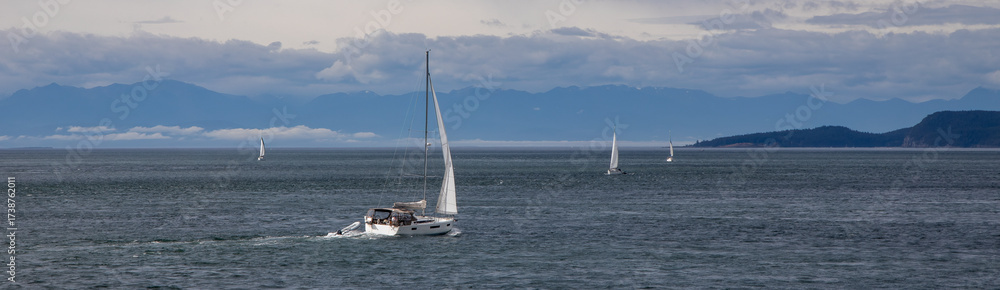 Obraz premium Multiple cruising sailboats transit a windy Rosario Strait going to and from the San Juan Islands