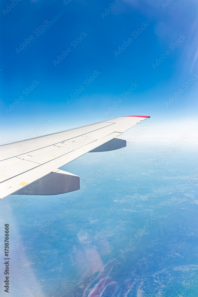 Fototapeta premium View from the airplane window at a beautiful blue clear sky and the airplane wing