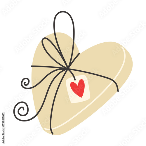 Heartshaped gift wrapped in beige paper with black ribbon and tag