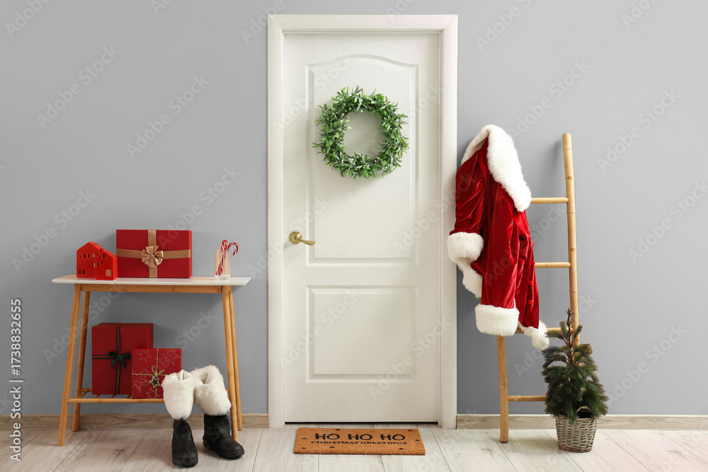 Obraz premium White door with wreath, Santa costume and Christmas gifts near color wall at home