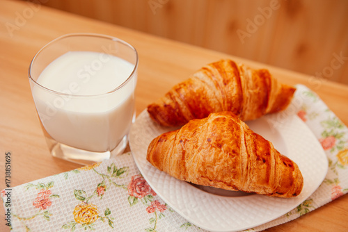 One glass of milk and two croissants on the table on the kitchen, sweet breakfast 