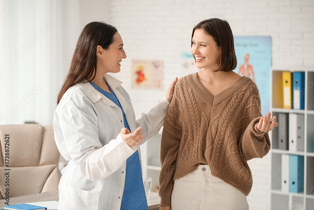 Fototapeta premium Happy young female doctor with patient in clinic