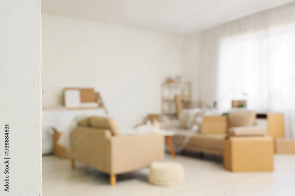 Fototapeta premium Blurred view of sofas with cardboard boxes in living room on moving day