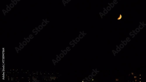 A crescent moon is in the night sky over the rural town in Fukuoka city, Japan. without sounds
