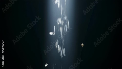 Shimmering silver particles falling through a bright light beam in