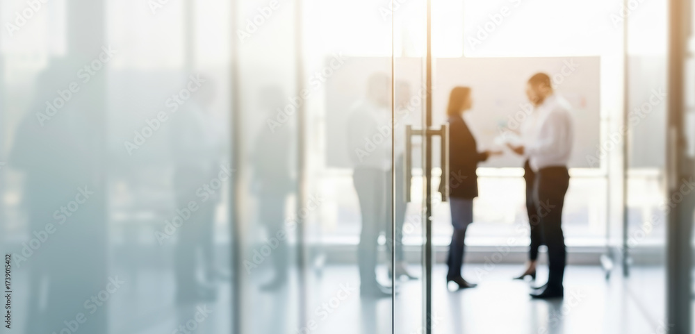 Fototapeta premium Two people talking in a bright modern office space with glass walls, exchanging ideas and engaging in conversation that reflects teamwork and professional communication.