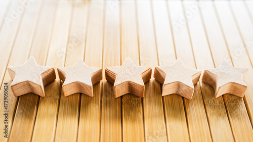 Foto Five wooden stars aligned on bamboo wooden surface