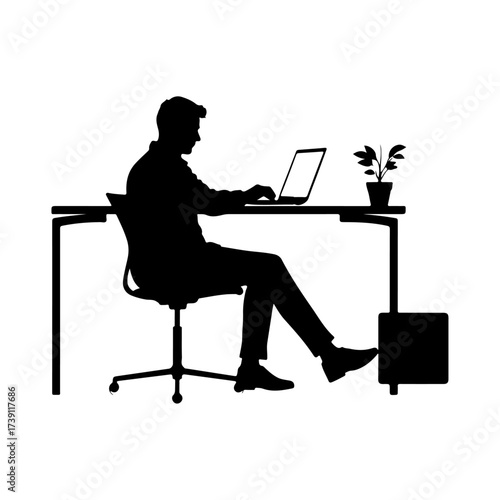 Silhouette of a man working on a laptop at a desk