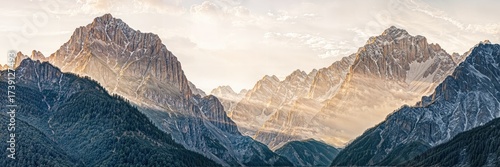 Majestic mountain range at sunrise with golden light illuminating the peaks and valleys in a serene landscape