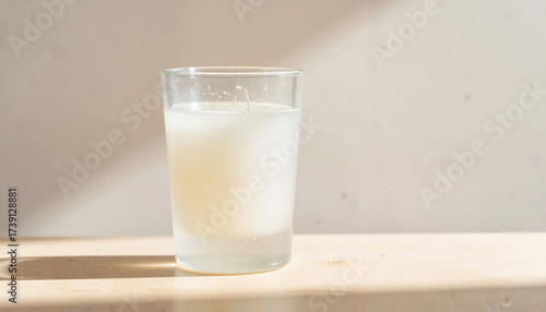 Glass of white beverage on wooden surface with natural light  