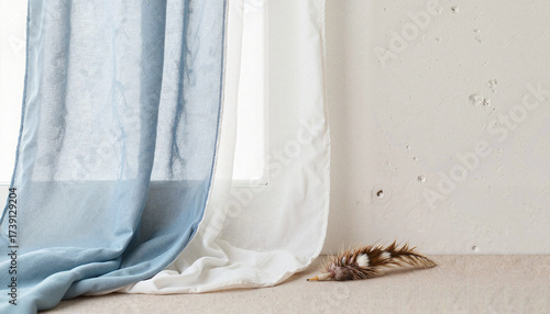 Sheer blue and white window curtains with a decorative feather.