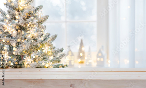 Home decorated Christmas tree and blur frosty window background with empty wooden table top for your product presentation