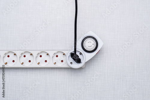 Top Shot einer Zeitschaltuhr in einer Steckerleiste auf einer weißen Resopal Platte