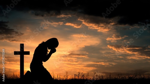 Kneeling Cross. Woman in prayer humbly bows down over the cross at sunset background