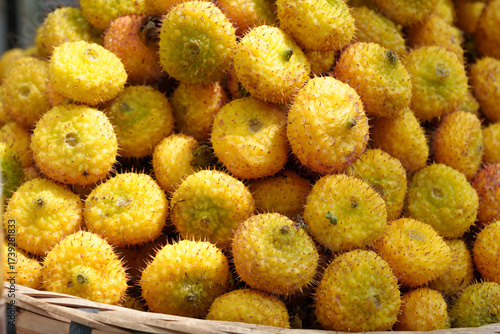 A basket full of bright yellow, fresh prickly pear fruits.