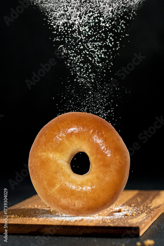 A bagel sprinkled with flour and sugar that gives a delicious feeling.