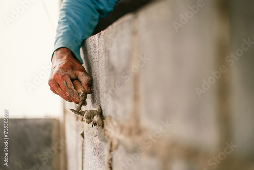 man is working on  wall, using a trowel to apply  layer of plaster