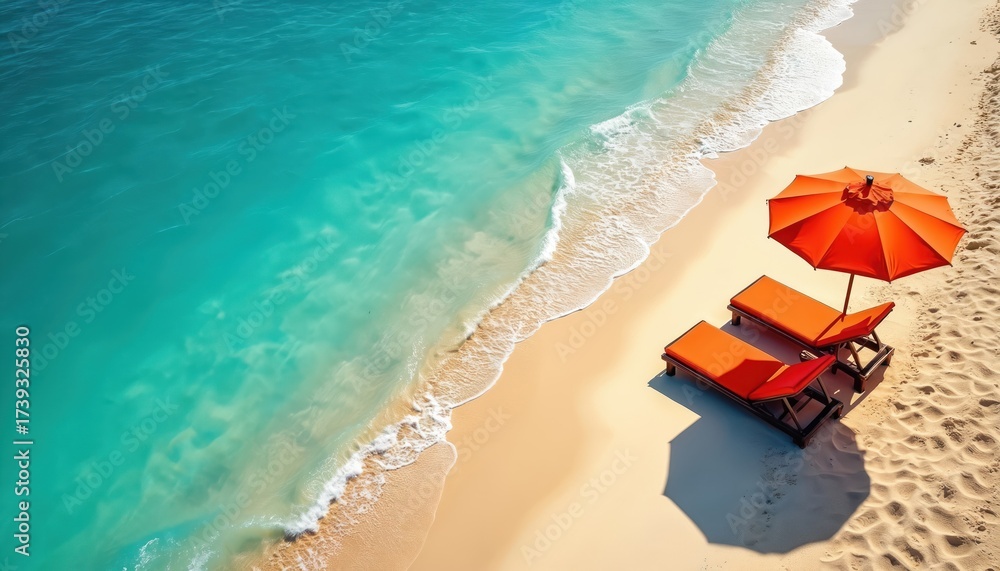 Naklejka premium Aerial view of tropical beach with calm turquoise ocean water. Gentle waves wash sandy shore. Bright orange umbrella, two lounge chairs on sand. Scene shows summer vacation relaxation at sunny