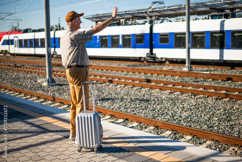 Wallpaper Mural Happy senior man is standing at railway station and waiting for arrival of the train. Senior people traveling. Torontodigital.ca