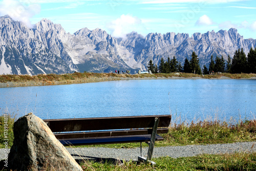 Scenic mountain view with a tranquil pond and a bench overlooking the landscape during a sunny day