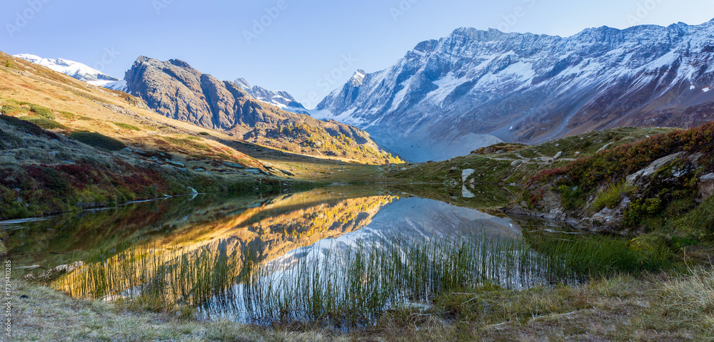 Obraz premium Mountain lake with reflection in swiss alps. Lake Guggisee perfectly reflects scenery in loetschental, valais switzerland