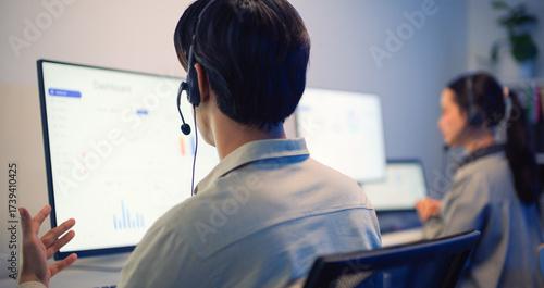 Customer service representatives wearing headsets working on computers in modern office, providing assistance and communication support.