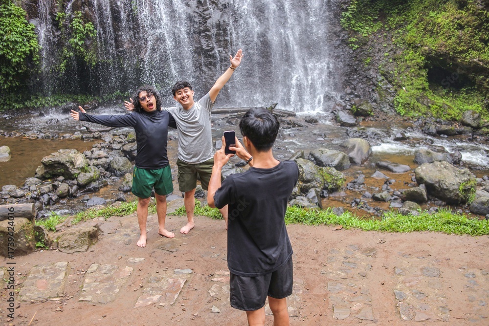 Obraz premium Friends Capture Joyful Memories At Stunning Waterfall During Tropical Vacation Adventure