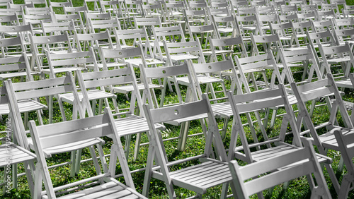 Rows of white folding chairs on green grass outdoors