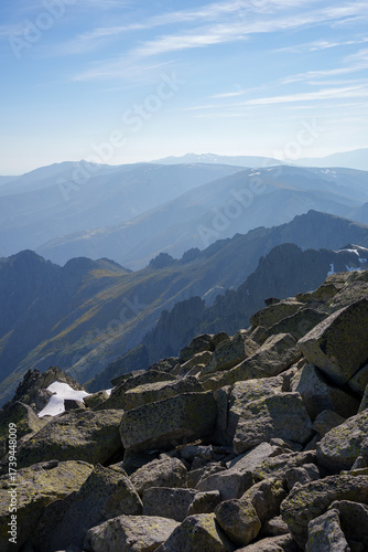 Expansive panoramic view over rocky peaks and mountain ranges of Sierra de Gredos, Spain, with distant layers under a blue sky and soft clouds, capturing wild and rugged highlands.
