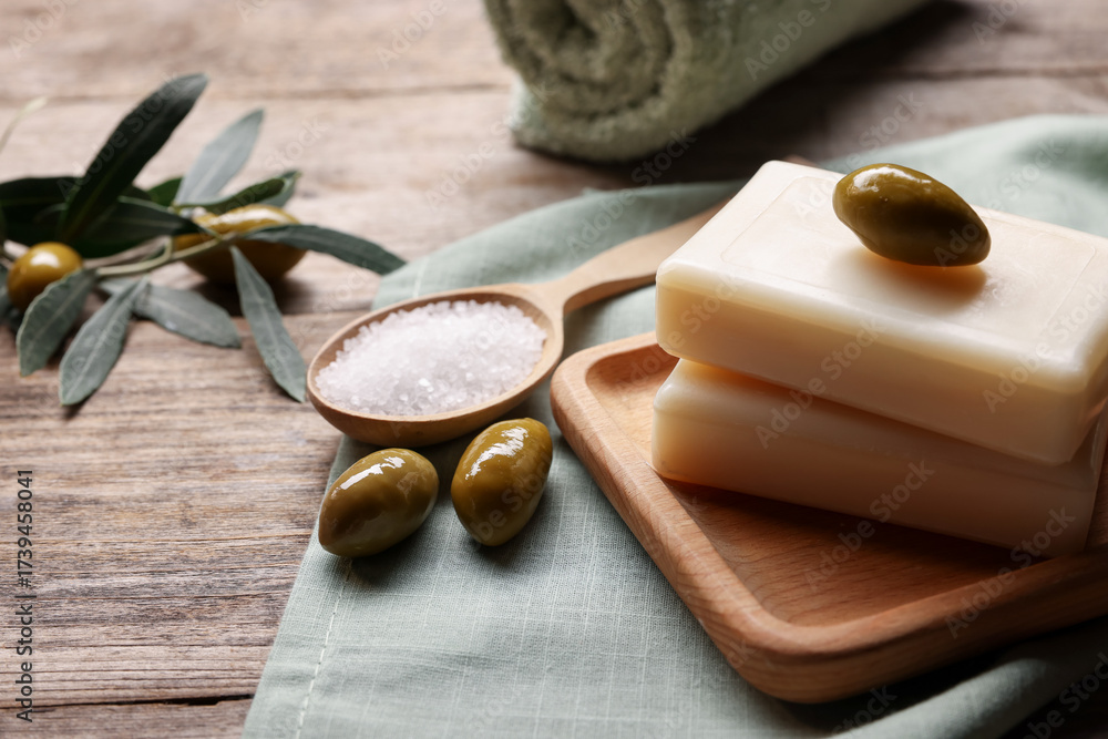 Fototapeta premium Natural soap bars, olives and sea salt on wooden table, closeup