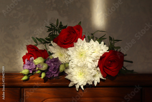 A beautiful bouquet of flowers lies on a wooden chest of drawers. A cozy, homey backdrop.