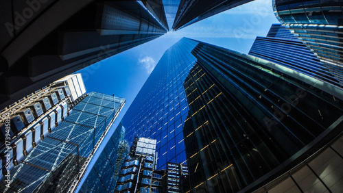 Modern skyscrapers and glass office buildings in business district, captured from low angle perspective with blue sky, symbolizing architecture, urban growth, corporate success, and city development.