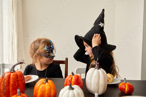 Two happy kids in colorful Halloween costumes enjoy a vibrant atmosphere filled with pumpkins and joy