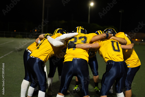 American football team huddling discussing strategy at night