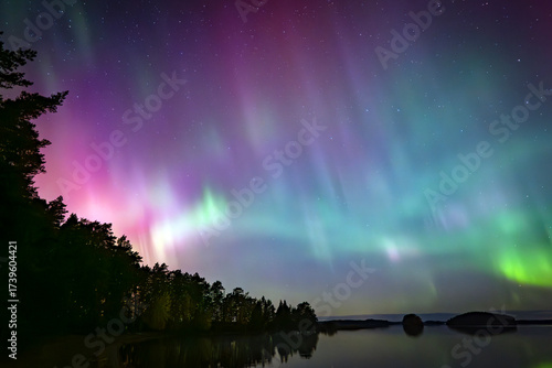 Nortern lights dancing over calm lake in Farnebofjarden national park in north of Sweden