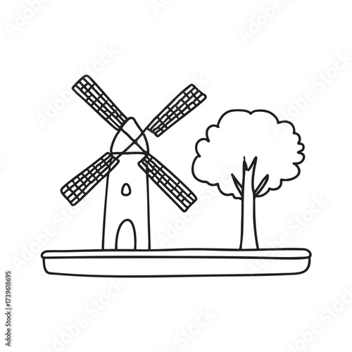 A windmill beside a tree casting long shadows across the field