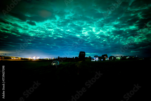 Northern lights dancing behinde the dark cloud over country landscape